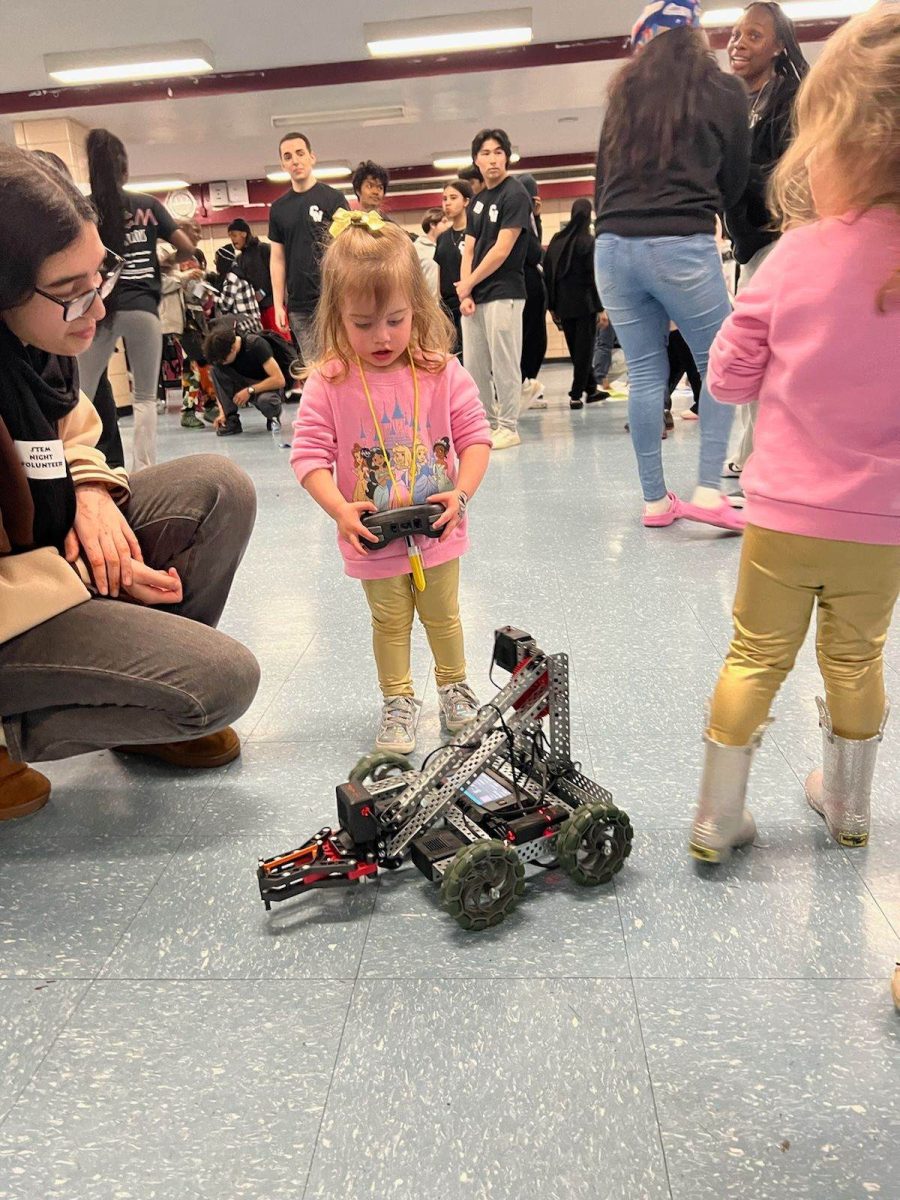 One of the many activities at STEM Night was hosted by Robotics, where they showcased their projects. Robotics member Noor Syar is pictured guiding Savanna Pizzarelli through the process of controlling one of their clawed robots.